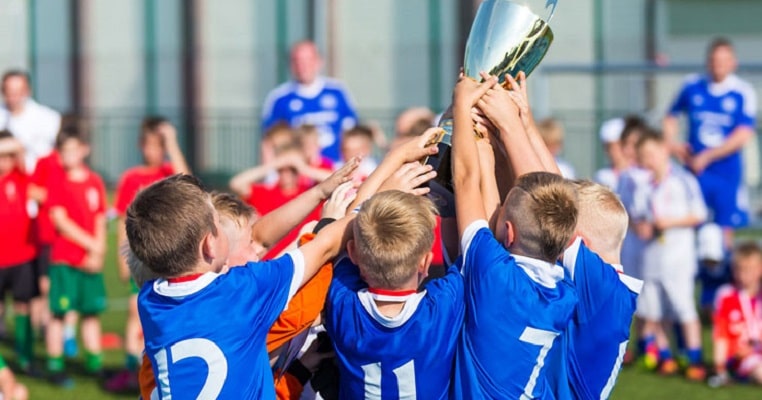 Foto de garotos segurando um troféu de campeonato de futebol